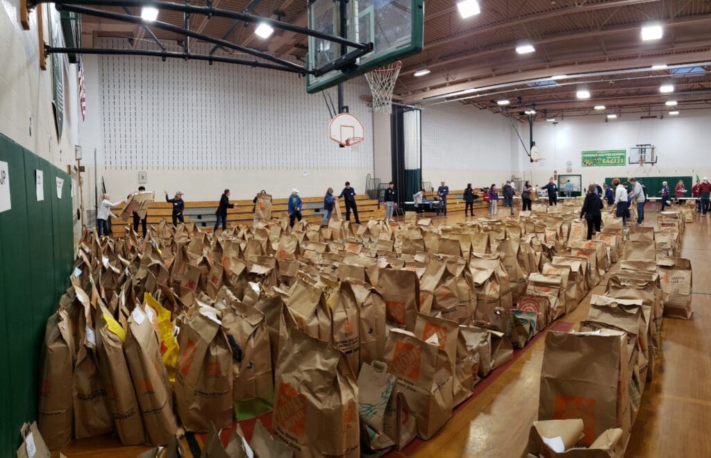 Gym filled with bags with a line of people passing the bags hand to hand. 